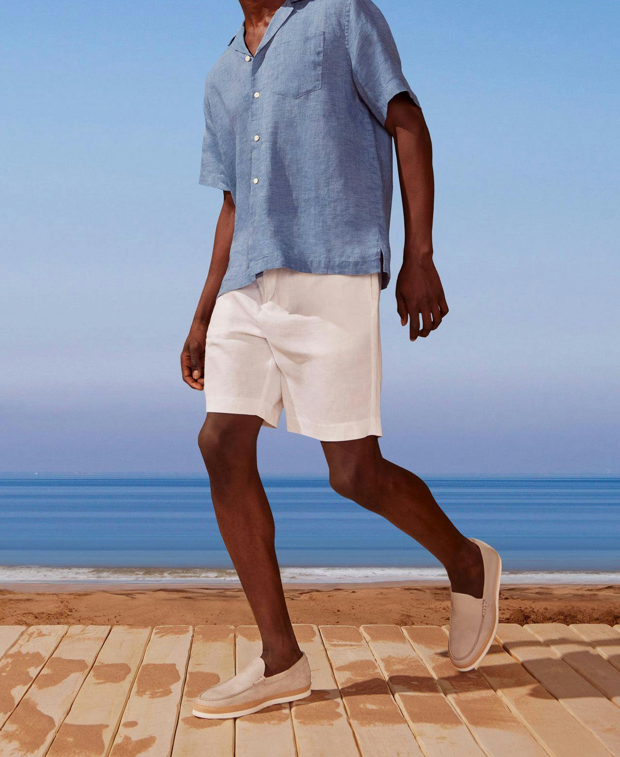 male model in polo and shorts with blue sky background