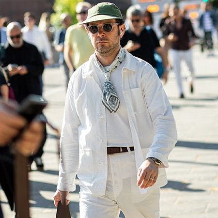 modèle masculin marchant dans la ville portant des lunettes de soleil, un chapeau, une écharpe et une surchemise