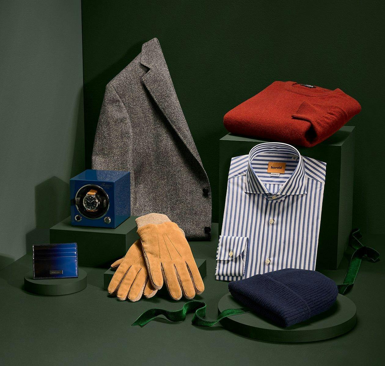 Manteau gris, portefeuille bleu, remontoir de montre bleu, gants en daim beige, chemise à rayures Harold, chapeau bleu marine et pull rouge