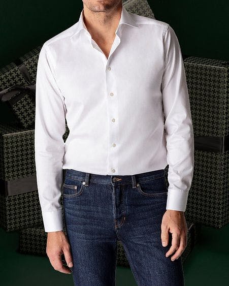 Mannequin masculin présentant chemise blanche et jean bleu sur fond vert foncé