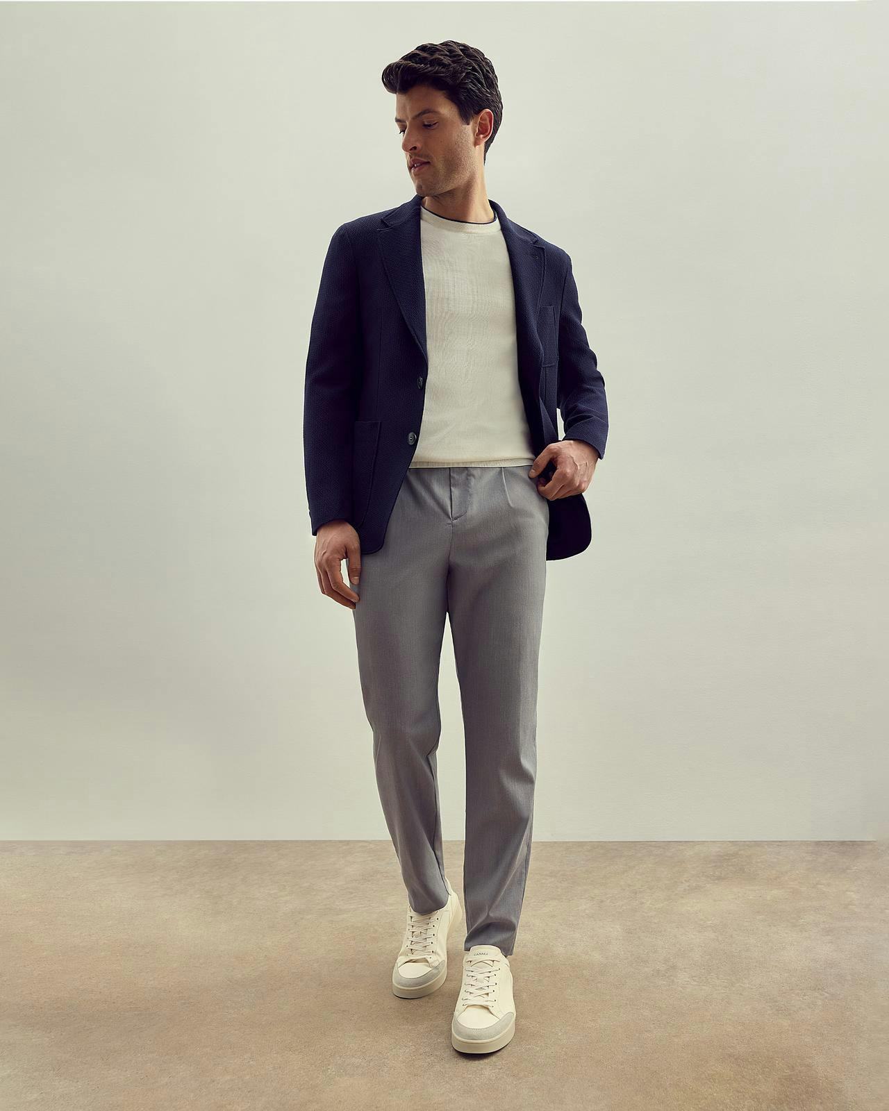 a male model in grey pants, a white t-shirt and a navy sports jacket