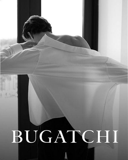 male facing window putting on bugatchi dress shirt
