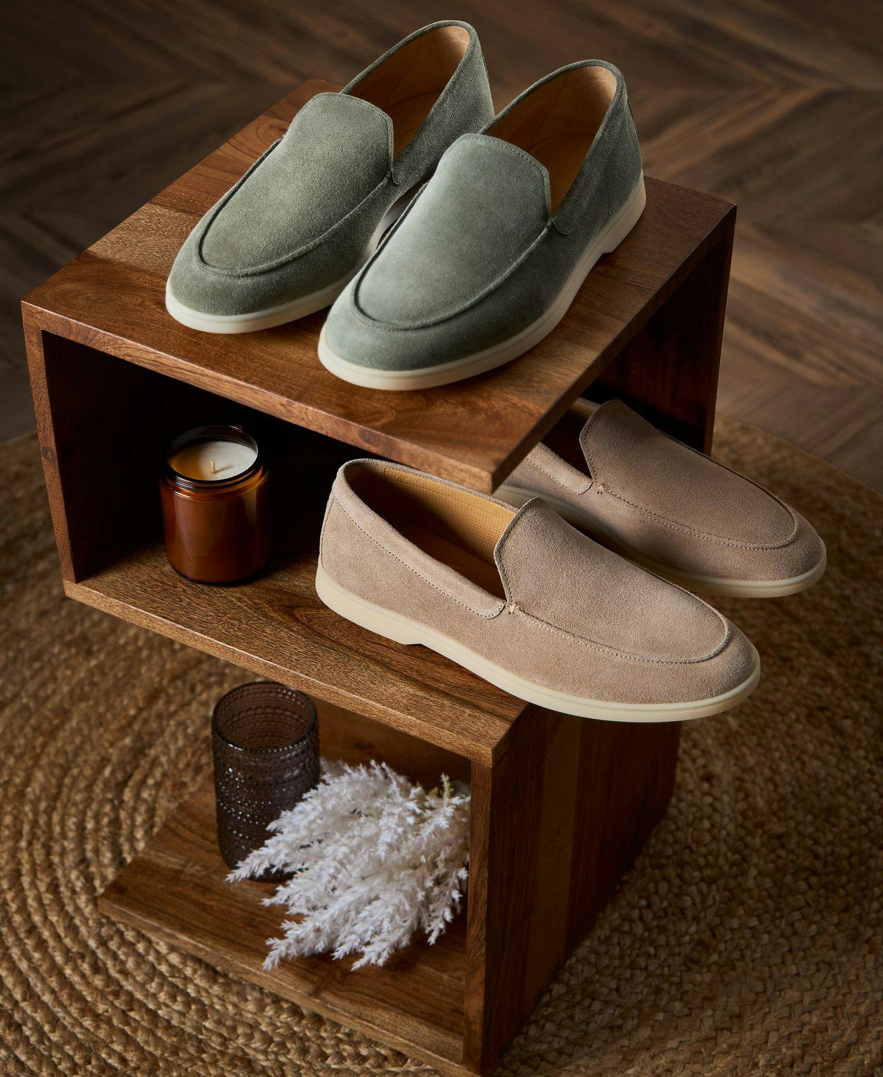 two pairs of loafers and two candles displayed on shelves ontop of carpet