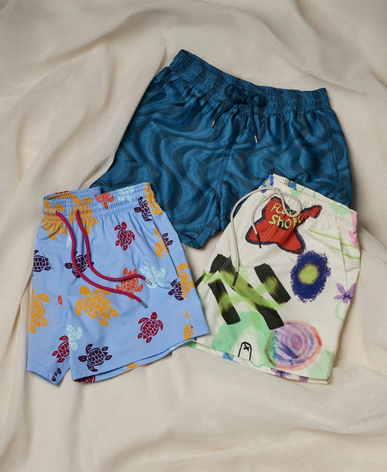 trois paires de shorts de bain à motifs colorés sur une couverture
