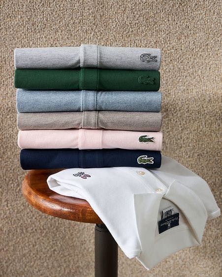 six different coloured polos folded on a side table and on one hanging off table