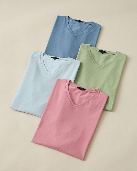 four v-neck t-shirts folded on beige backdrop