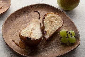 wooden plate with a cut pear and grapes