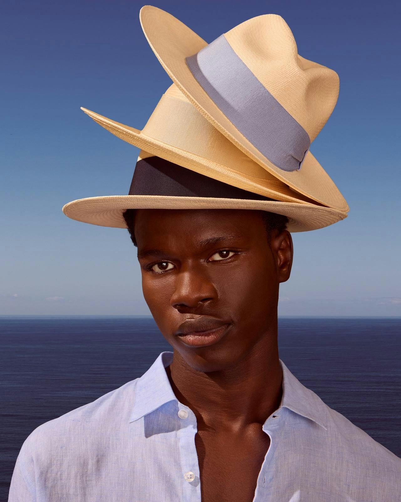 Un homme avec trois chapeaux empilés sur sa tête.