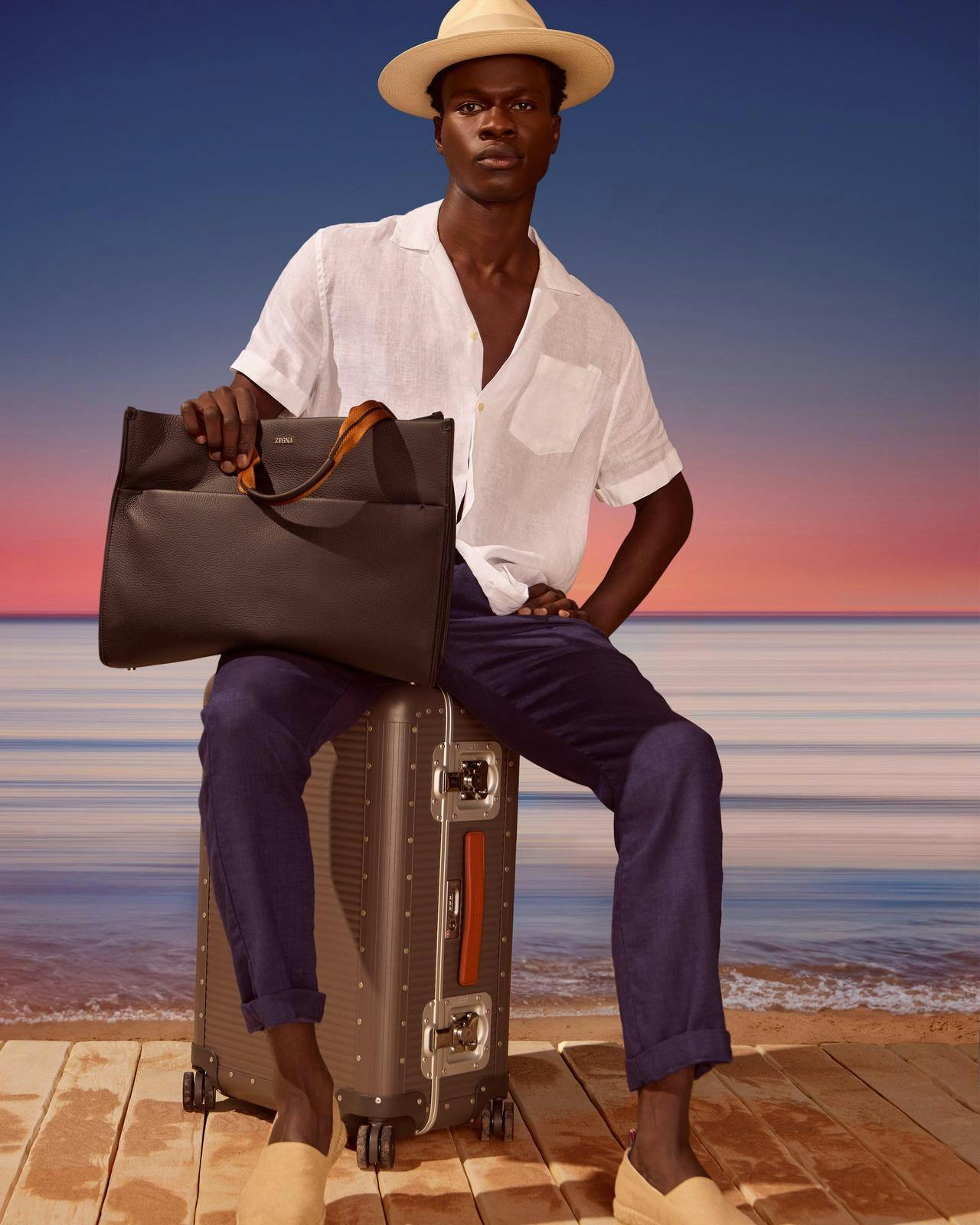 Un homme assis sur une valise avec une mallette à la main.