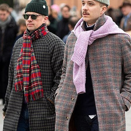 Deux hommes portant des manteaux et des foulards marchant dans une rue