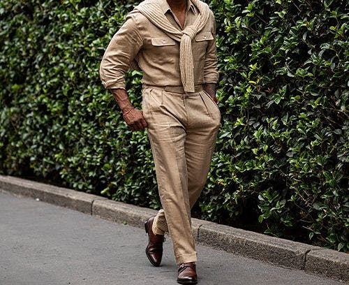 a man in a tan suit and sunglasses walking down a street