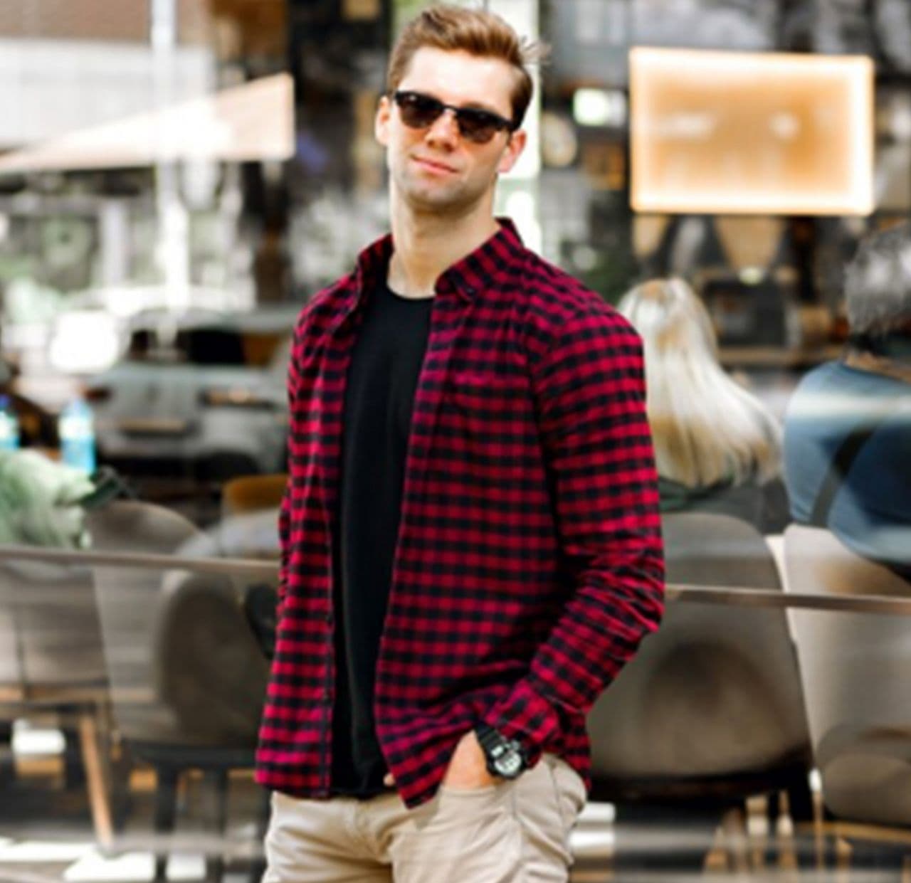 male model posing with one hand in pocket in the city wearing checkered sport shirt, t-shirt and jeans.