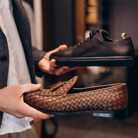 male hands holding sneaker and loafer