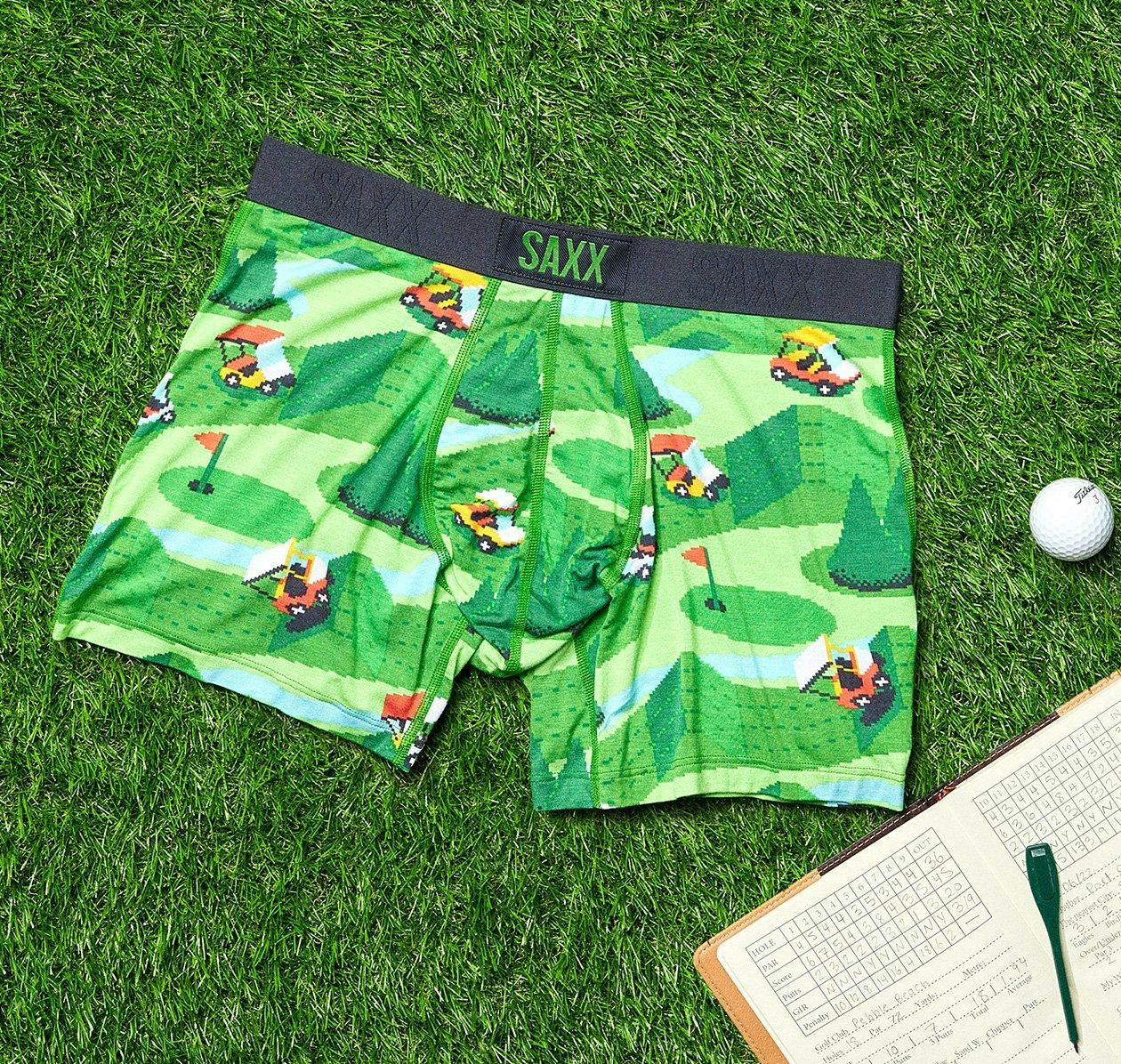 golf patterened saxx boxers, golf ball and book displayed on grass