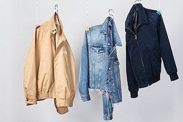 three lightweight jackets hanging on hooks on grey backdrop