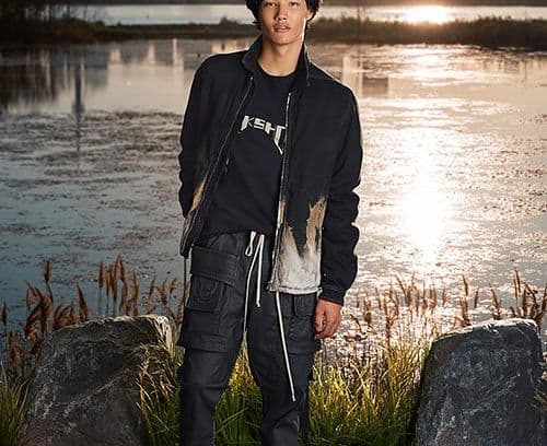 Male model wearing DRKSHDW light bomber jacket, graphic t-shirt and cargo pants showcasing todays take on 2000s style