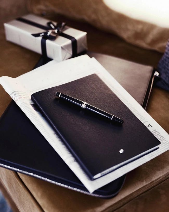 un carnet mont blanc, un stylo et un cadeau emballés sur une table